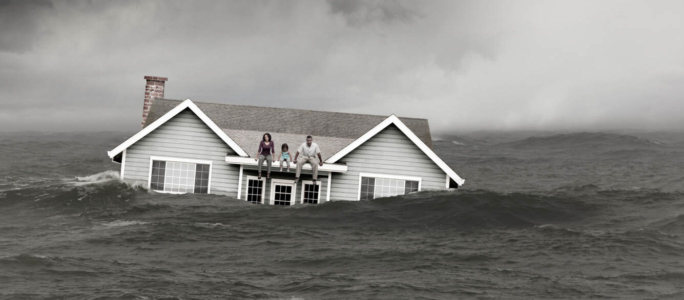 Family sitting on roof of house floating in sea Family sitting on roof of house floating in sea