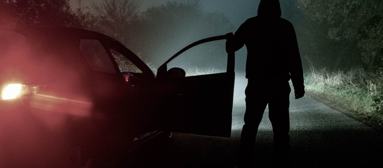 A spooky, mysterious hooded figure, standing next to a car with the door open. Looking down a moody, foggy, road at night A spooky, mysterious hooded figure, standing next to a car with the door open. Looking down a moody, foggy, road at night