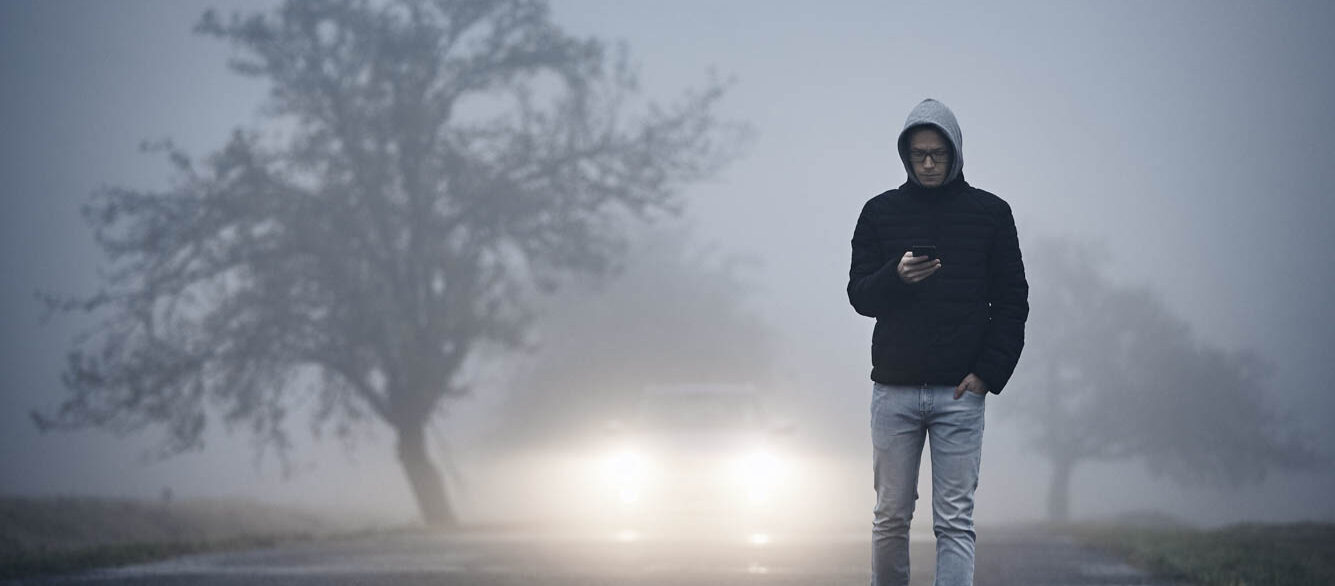 Man Using Phone While Walking On Road During Foggy Weather Man Using Phone While Walking On Road During Foggy Weather