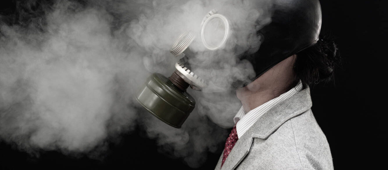 Businessman wearing a gas mask on a black background. Businessman wearing a gas mask on a black background.