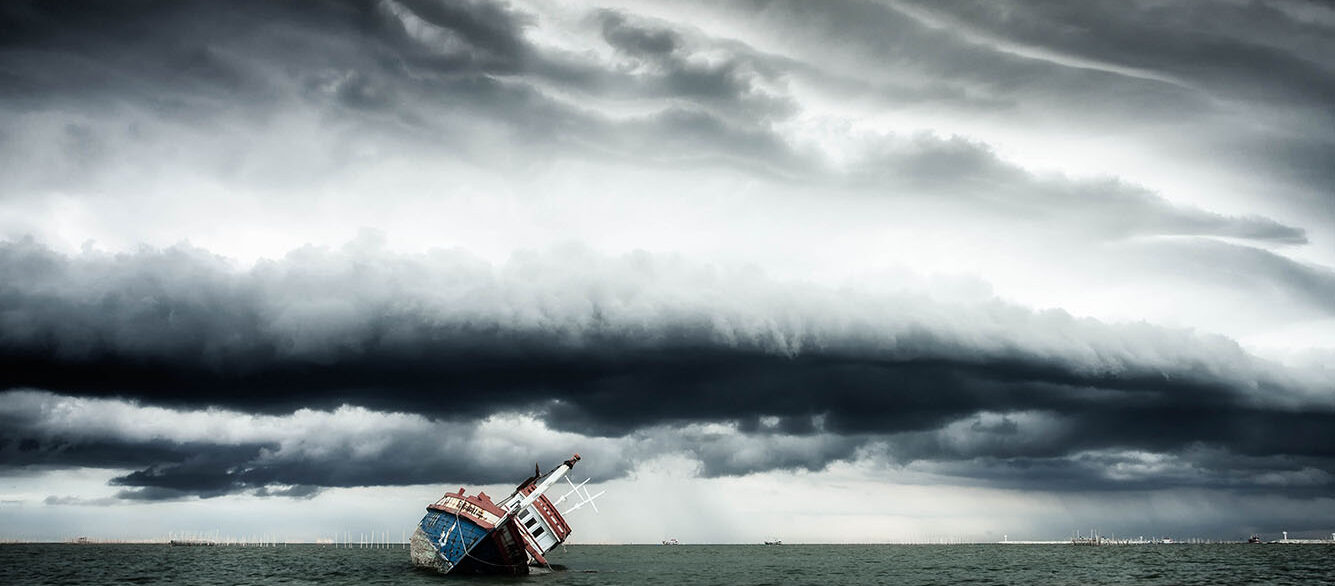Sinking ship on ocean with cloudy sky in background Sinking ship on ocean with cloudy sky in background