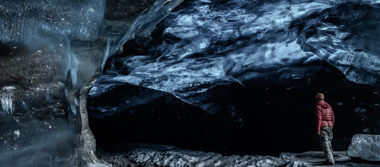 An explorer entering an ice cave An explorer entering an ice cave