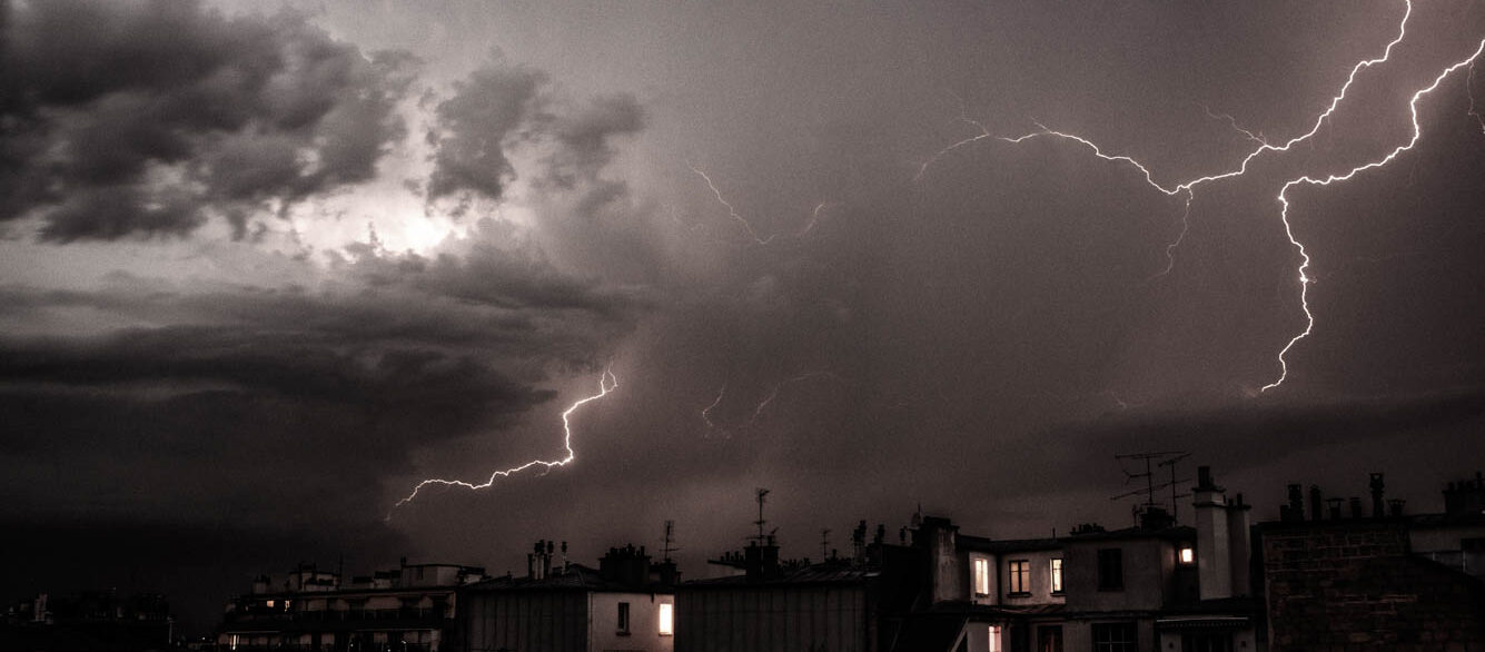 Buildings In City Against Thunderstorm At Night