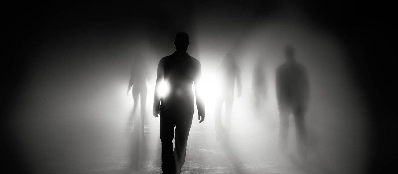 Silhouettes of people walking into light